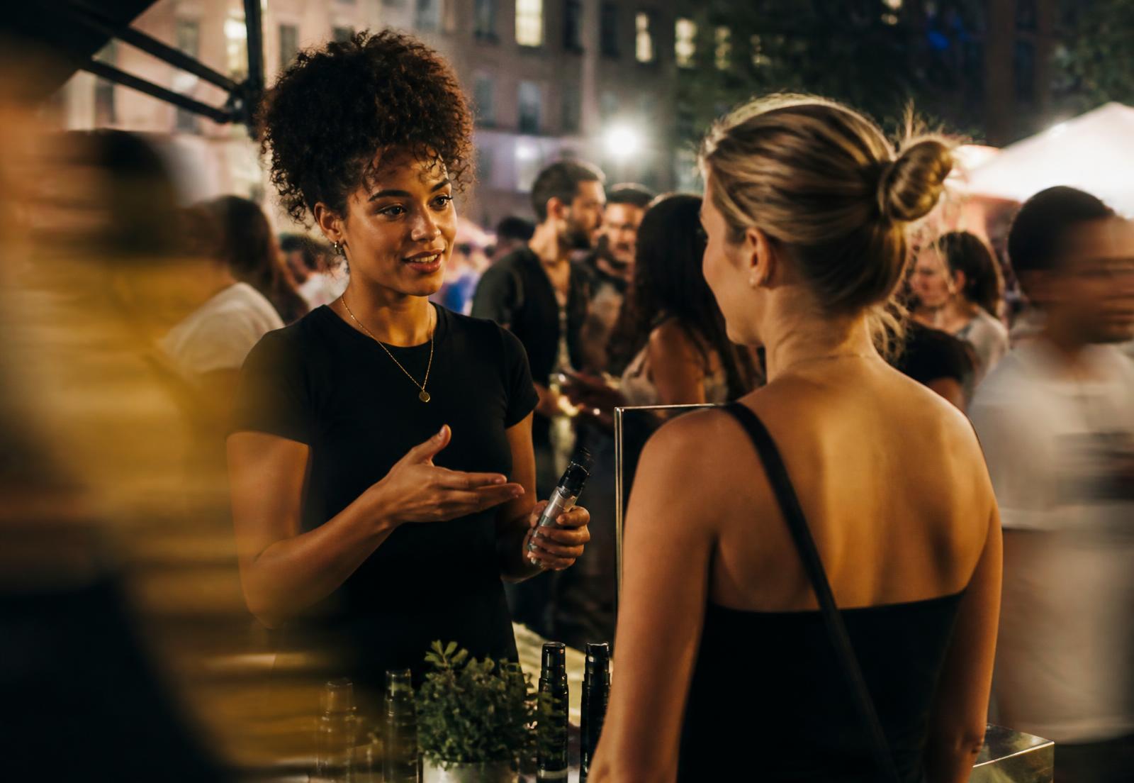 A brand representative in conversation with a customer at an evening city activation